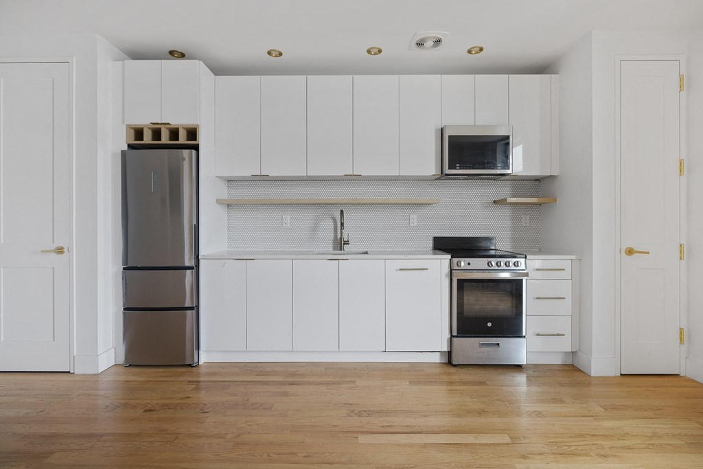 a white kitchen with stainless steel appliances and white cabinets